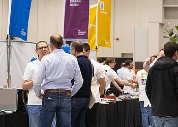 Messestand mit Besuchern am Tag der Technik von HENNLICH